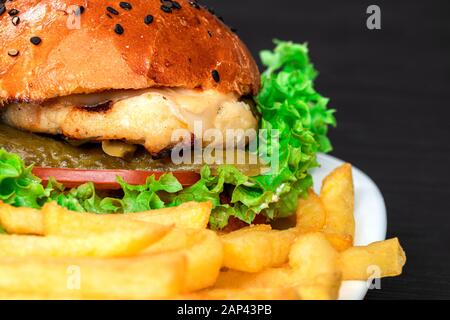 délicieux hamburger appétissant sur un terrel blanc avec des frites sur fond gris Banque D'Images