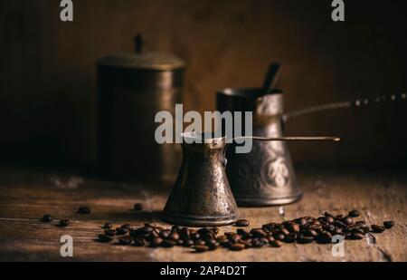 Ancienne cafetière et grain de café sur une table en bois rustique. Café oriental vintage sur fond sombre. Toujours la vie. Banque D'Images