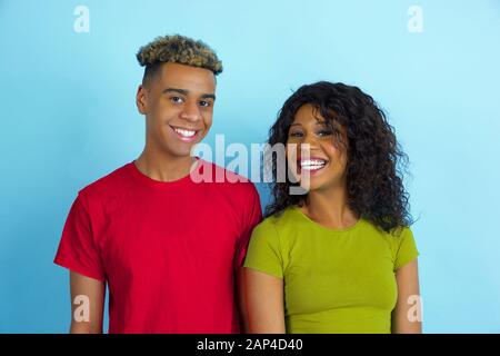 Close up de jeunes afro-américains émotionnel l'homme et la femme dans des tenues colorées posant sur fond bleu. Beau couple. Concept d'émotions humaines, soins du visage, expession, ad, les relations d'amitié. Banque D'Images