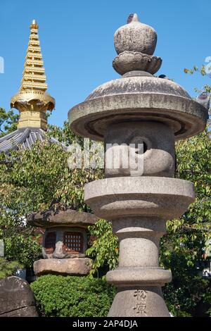 La vue des lanternes en pierre traditionnelles (Tachidoro) avec la pointe de la pagode (sorin) sur le fond dans le temple Isshin-ji. Osaka. Japon Banque D'Images