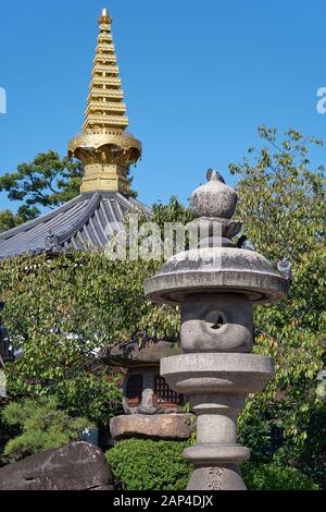 La vue des lanternes en pierre traditionnelles (Tachidoro) avec la pointe de la pagode (sorin) sur le fond dans le temple Isshin-ji. Osaka. Japon Banque D'Images