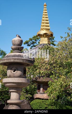 La vue des lanternes en pierre traditionnelles (Tachidoro) avec la pointe de la pagode (sorin) sur le fond dans le temple Isshin-ji. Osaka. Japon Banque D'Images