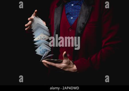 Magicien montre trick avec des cartes à jouer, fond sombre Banque D'Images