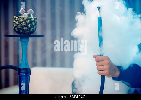 L'homme tient le hookah, main dans la chicha de fumée Banque D'Images