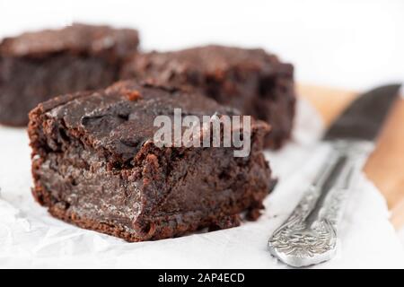 gros sur les brownies de chocolat végétalien à base de plantes faites de patates douces avec un couteau d'argent sélectif se concentrer sur un fond blanc pour l'espace de copie Banque D'Images