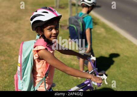 Écolière assise sur un vélo et portant un casque Banque D'Images