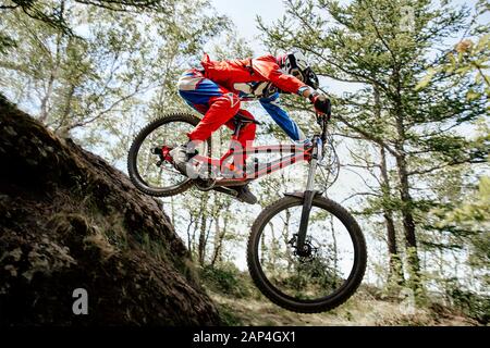 le pilote saute la montagne dans la compétition de sentier forestier en descente Banque D'Images