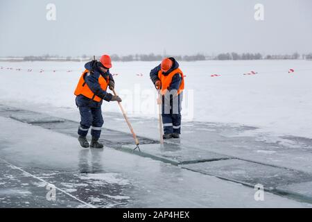 Les employés radeau des blocs de glace le long d'une chaîne coupée un lac gelé Banque D'Images