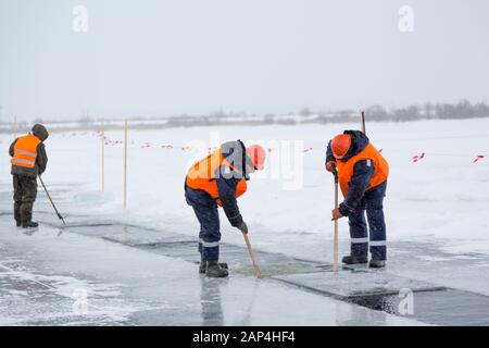 Les employés radeau des blocs de glace le long d'une chaîne coupée un lac gelé Banque D'Images