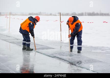 Les employés radeau des blocs de glace le long d'une chaîne coupée un lac gelé Banque D'Images