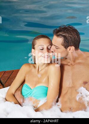 Heureux couple kissing in the jacuzzi pendant des vacances en spa Banque D'Images