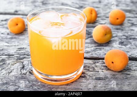 Jus frais d'abricot avec abricots et glaçons dans un verre sur le fond de vieux planches. Boissons non alcoolisées d'été. Gros plan. Banque D'Images