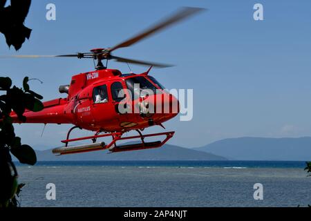 Atterrissage en hélicoptère rouge après un vol panoramique au-dessus de la Grande barrière de corail, Queensland, Australie avec eau et montagnes dans la batchground Banque D'Images