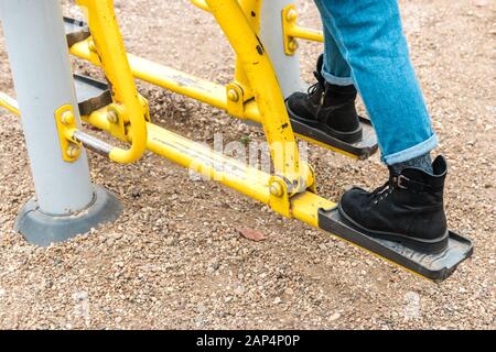 gros plan sur les jambes d'une femme avec des chaussures décontractées et un jean sur une salle de conditionnement physique extérieure, une machine d'entraînement Banque D'Images