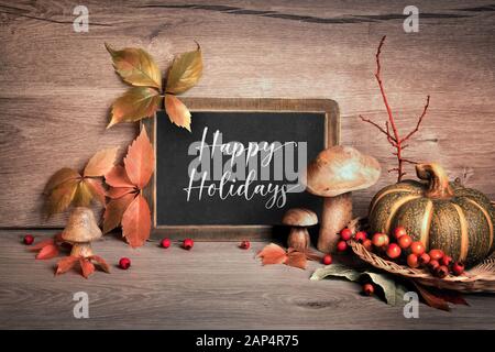 Arrangement d'automne à la citrouille et le lettrage "Happy Holidays" sur un tableau. Décorations naturelles avec des baies d'automne, les feuilles d'automne, red berry rowan Banque D'Images