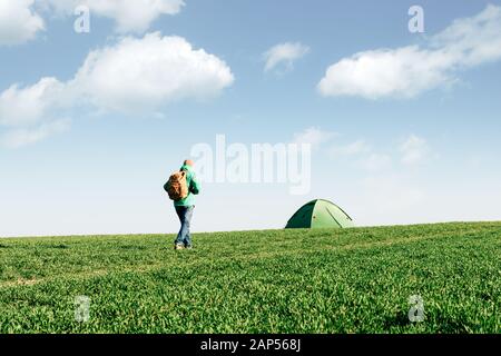 Sac à dos avec touristiques aller à sa tente sur le terrain de l'été. Le bleu ciel nuageux. Concept de voyage Banque D'Images