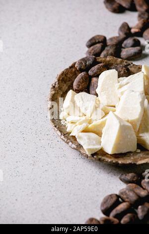 Des morceaux de haché beurre de cacao biologique dans l'artisanat en céramique et les fèves de cacao plus de gray background. Banque D'Images