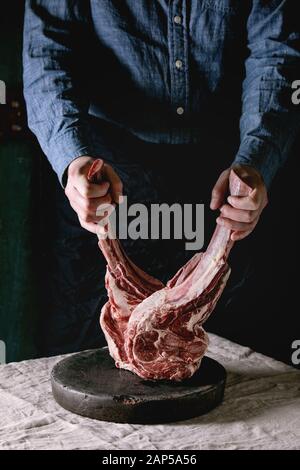 Man's hands holding crus crus steaks de boeuf Black Angus tomahawk sur les os sur le linge de table cloth. Style rustique Banque D'Images