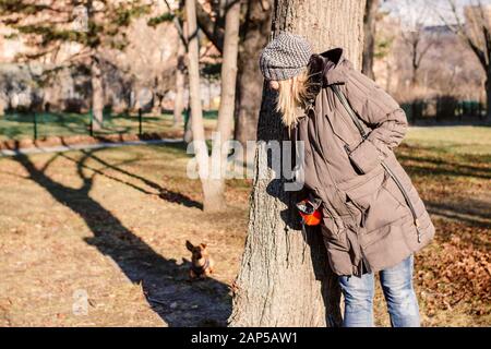 Femme et son petit chien jouant se cachent et cherchent dans un parc. PET et activité extérieure concept. Banque D'Images