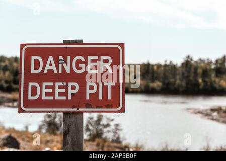 Signe de danger de fosse profonde. Signalisation d'avertissement rouge sur le terrain pour la sécurité sur le lieu de travail. Faites attention Banque D'Images