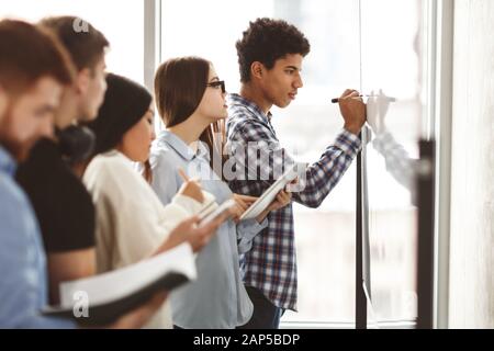 Les étudiants qui écrivent des équations d'algèbre sur tableau blanc en classe Banque D'Images