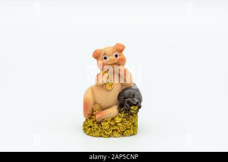 Figurine d'une petite piggie assise sur une pile d'or, fond blanc Banque D'Images