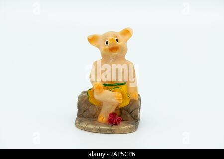 Figurine d'une petite piggie assise sur un banc, fond blanc Banque D'Images