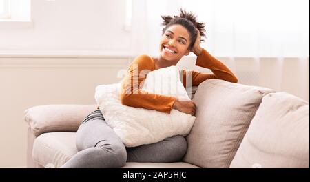 Afro American Woman Assis Sur Canapé Embring Pillow Intérieur, Panorama Banque D'Images