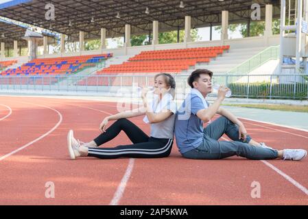 Portrait d'un couple hispanique mignon buvant de l'eau et se reposant après l'écoulement sur la piste à studium, concept sain et sportif Banque D'Images