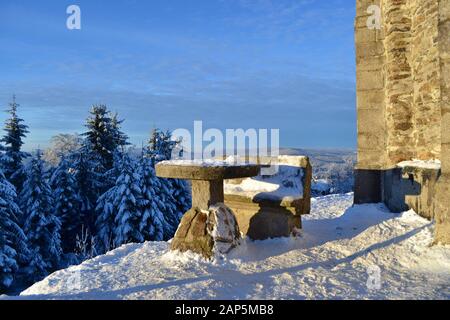 Table en pierre avec banc recouvert de neige. Lieu de repos avec vue magnifique sur la forêt et les montagnes de Jizera, République tchèque. Banque D'Images