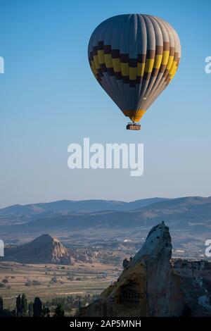 Cappadocia, Turquie: Montgolfière à l'aube sur l'église Saint-Jean-Baptiste (château de Cavusin), célèbre église grotte du 5ème siècle au sommet de la colline Banque D'Images