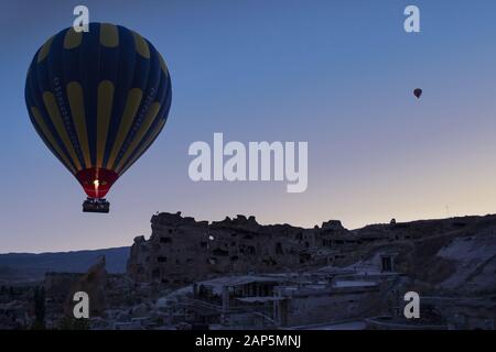 Cappadocia, Turquie: Montgolfière à l'aube sur l'église Saint-Jean-Baptiste (château de Cavusin), célèbre église grotte du 5ème siècle au sommet de la colline Banque D'Images