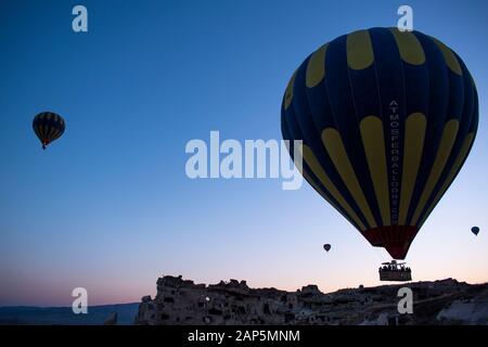 Cappadocia, Turquie: Ballons d'air chaud à l'aube sur l'église de Saint Jean-Baptiste (château de Cavusin), célèbre église de caverne du 5ème siècle au sommet de la colline Banque D'Images