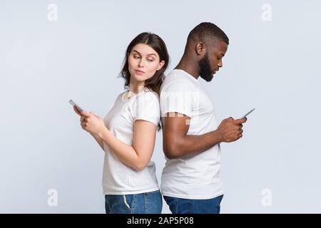 Curieuse Femme Se Cachant Sur L'Épaule Comment Son Boyfriend Texting Avec Quelqu'un Banque D'Images