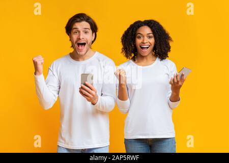 Portrait de jeune homme et de jeune femme surplaisante avec les smartphones Banque D'Images