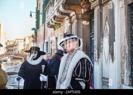 Venise, Italie - 10 février 2018: Deux hommes en costume, l'un porte le masque médecin Medico della Peste Plague pendant le Carnaval de Venise, canal et Banque D'Images