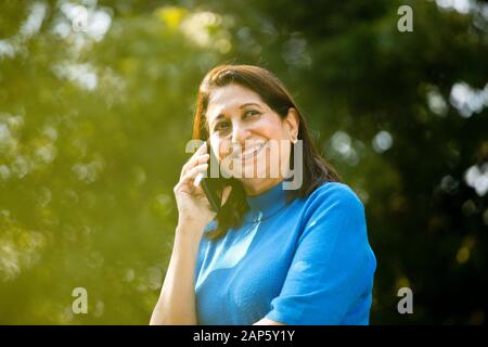 Heureuse femme senior utilisant le téléphone au parc Banque D'Images