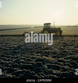 Tracteur avec un non-réversible, 7 coulter Ransome labour charrue à travers les chaumes du givre sur un froid matin d'automne, Hampshire, novembre, Banque D'Images