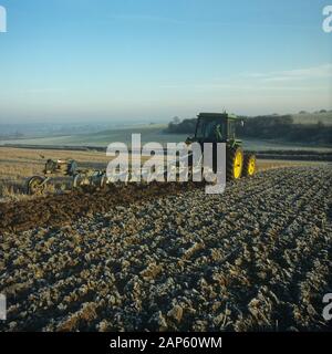 Tracteur avec un non-réversible, 7 coulter Ransome labour charrue à travers les chaumes du givre sur un froid matin d'automne, Hampshire, novembre, Banque D'Images