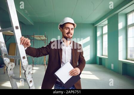 Homme barbu de l'entrepreneur dans un casque blanc dans une chambre sur un site de construction Banque D'Images