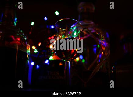 Vue en angle bas sur verre isolé avec rhum. Bokeh avec des couleurs éclatantes et des bouteilles floues arrière-plan. Banque D'Images