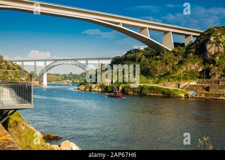 Vue sur un bateau traditionnel vintage naviguant sur le fleuve Douro et certains des ponts qui le traversent Banque D'Images