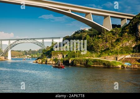 Vue sur un bateau traditionnel vintage naviguant sur le fleuve Douro et certains des ponts qui le traversent Banque D'Images