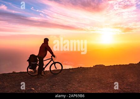 Mountain Bicycle Rider avec sac à dos voyage au-dessus de l'arrière-plan sunrise, Lanzarote Canary Island Banque D'Images