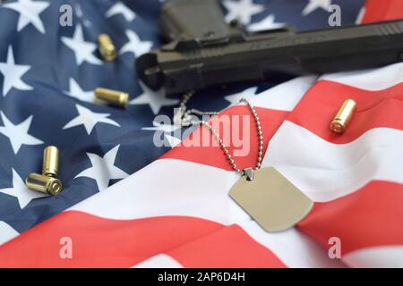 Jeton d'étiquette de chien de l'armée avec balles de 9 mm et pistolet se trouve sur le drapeau américain replié. Un ensemble d'articles anciens combattants militaires américains ou de trophées de vieux devoir Banque D'Images