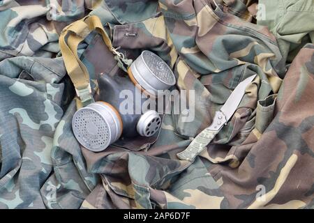 Les soldats stacker masque à gaz soviétique repose avec couteau sur des vestes de camouflage kaki vertes. Kit post-apocalypse Surviving items Banque D'Images