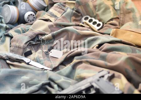 Les soldats stacker masque à gaz soviétique se trouve avec un pistolet et un couteau sur des vestes de camouflage kaki vertes. Étiquettes pour chien et porte-fusée en laiton. Post apocalypse survivre Banque D'Images