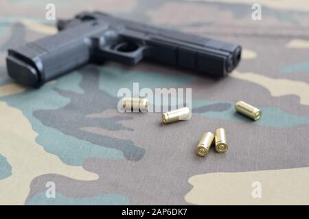 balles de 9 mm et pistolet sur tissu vert camouflage. Un ensemble d'éléments de plage de prise de vue ou un kit d'autodéfense. Golden Shells près du pistolet Banque D'Images