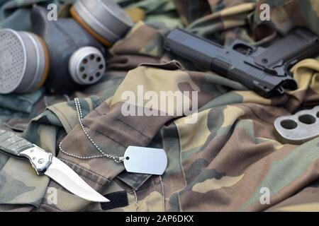 Les soldats stacker masque à gaz soviétique se trouve avec un pistolet et un couteau sur des vestes de camouflage kaki vertes. Étiquettes pour chien et porte-fusée en laiton. Post apocalypse survivre Banque D'Images