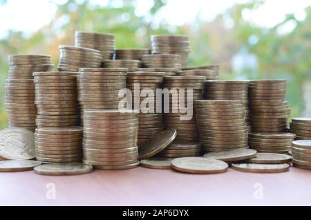 Une grande quantité de pièces de monnaie ukrainienne brillante de 1 hryvnia s'empile sur une table en bois sur fond d'arbres verts flous. Le concept d'affaires et riche l Banque D'Images